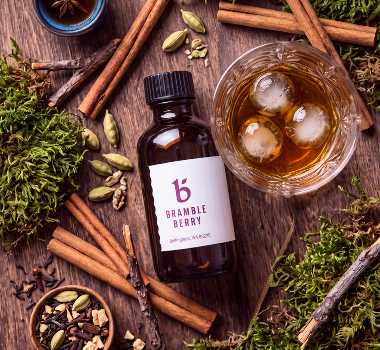 fragrance bottle surrounded by fall spices and a drink