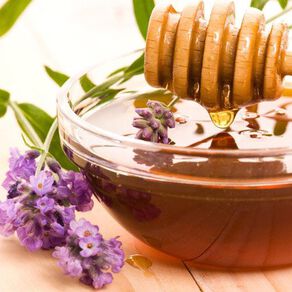 Honey in a bowl surrounded by a lavender flower