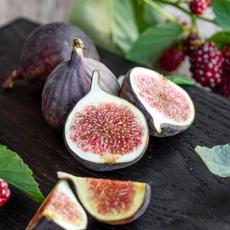 Figs cut in half and uncut on a wooden table and cranberries in trees 