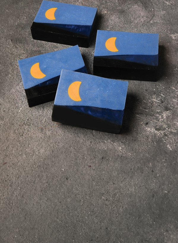 soaps designed like a night sky with a moon on a dark marble counter