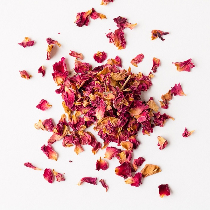 Dried red rose petals on a white background
