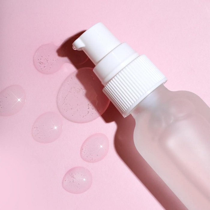 a bottle of face serum on a pink background