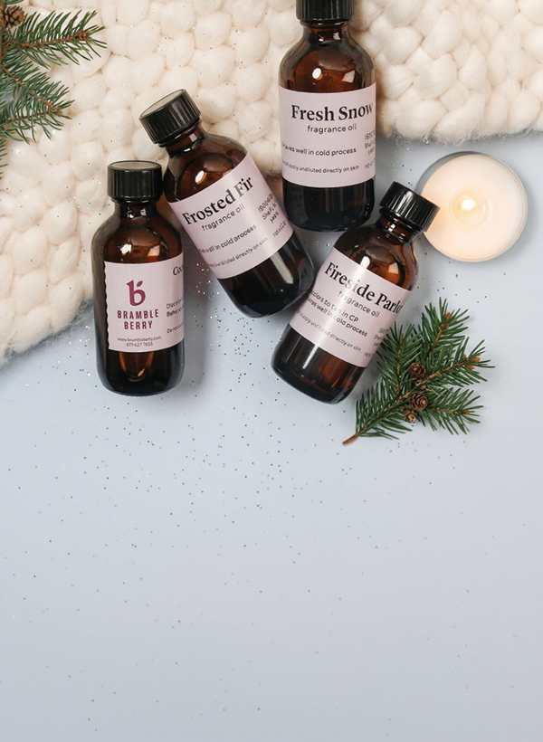 fragrance bottles with cozy scarf, pine sprigs, and a candle