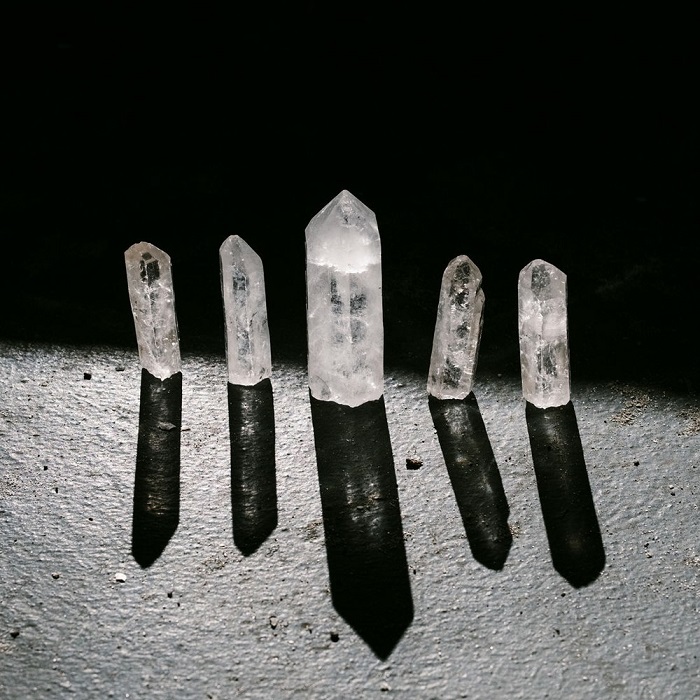 A series of quartz crystals lit by white light against a black background