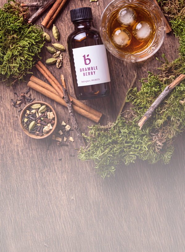 Fragrance bottle surrounded by fall spices and a drink