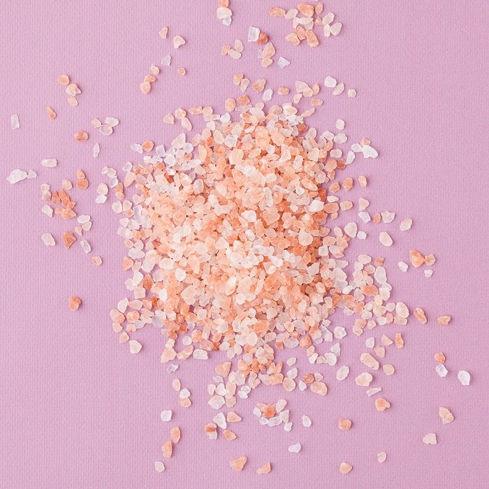 Medium grain pink sea salt against a pink background