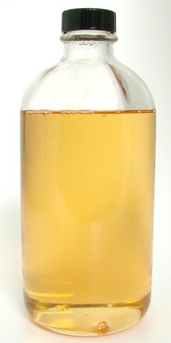 A bottle of fixed fragrance oil. The oil inside is liquid, clear, and homogenous
