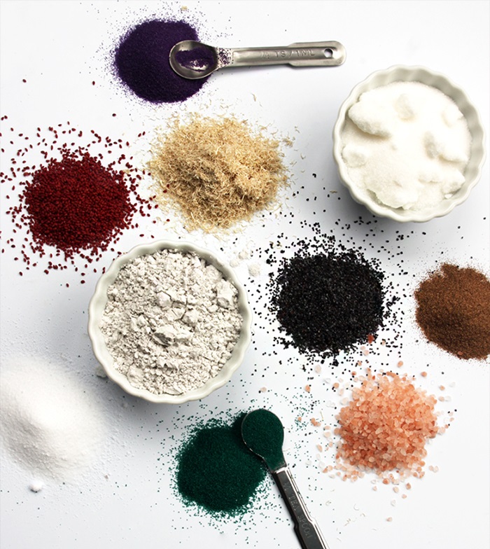 piles of multicolored powder exfoliants on a white surface