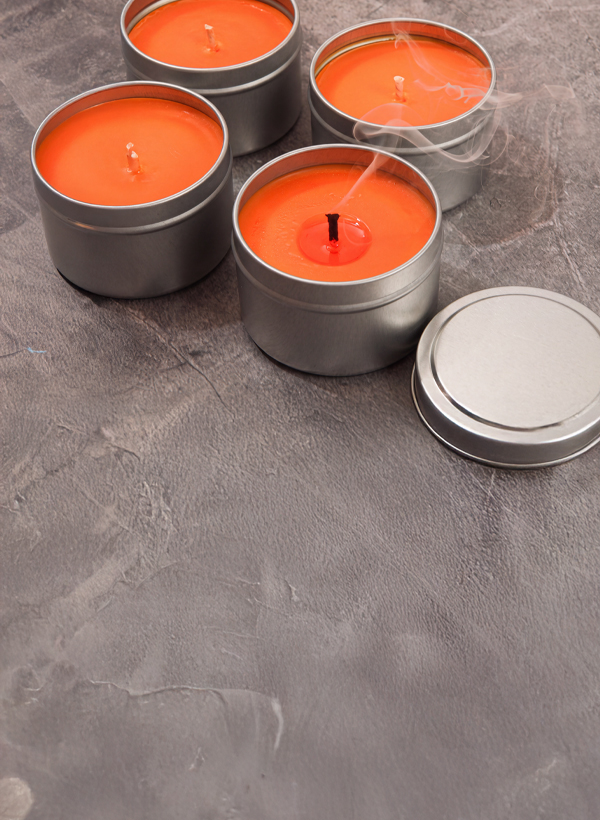 orange candles in silver tins on a gray countertop