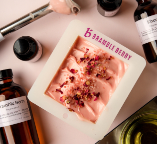 top view of a finished loaf of pink soap and various supplies