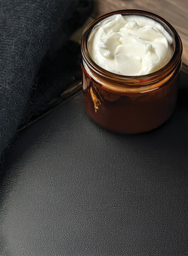 open container of white body cream against a dark background